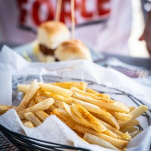 Tasty French fries with seasoning, served alongside mini burgers in a casual dining setting.