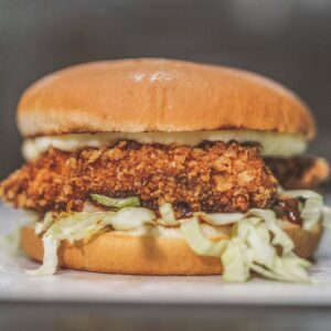 Delicious crispy chicken sandwich with lettuce and sauce served on a bun.