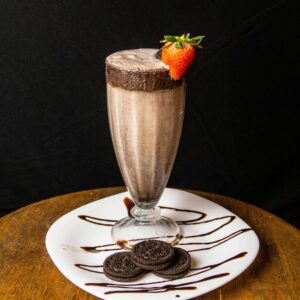 Indulge in a creamy chocolate milkshake garnished with a fresh strawberry and served with cookies.