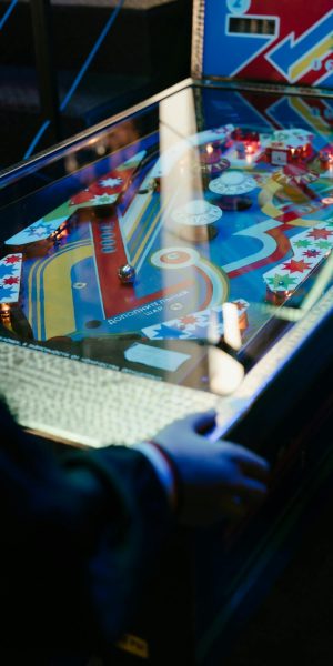 Colorful vintage pinball machine illuminated in a retro arcade setup with a player engaging.